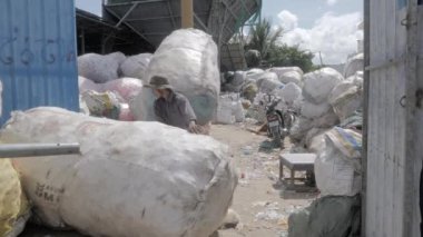 Phnom Penh - Kamboçya - 03 -12- 2022 - Plastik şişelerle dolu ve ağır torbalar taşıyan işçiler