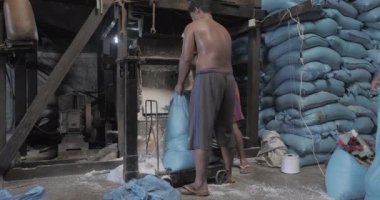 Phnom Penh - Kamboçya - 03 - 28 - 2022 - işçiler çuvala tuz doldurmak için kürek kullanırken, diğerleri fabrikada tuz torbaları hazırlıyor.
