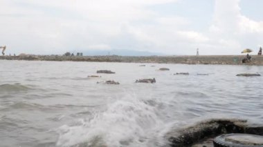 close up of waves hitting the sea coast. Bamboo cages filled with live crabs floating in the background