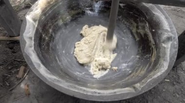 Bir tavanın içinde ahşap çubukla palmiye şekerini kalınlaştıran bir çiftçiye yaklaş. 