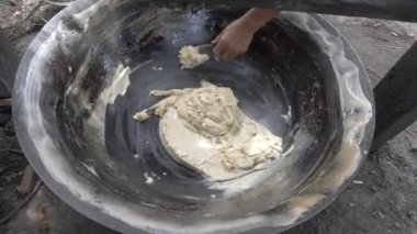 close up of a farmer removing paste of the palm sugar at the bottom of the wook cooking