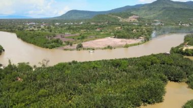 Nehirde yüzen bir teknenin insansız hava aracı görüntüsü. Arkaplan olarak dağlar  