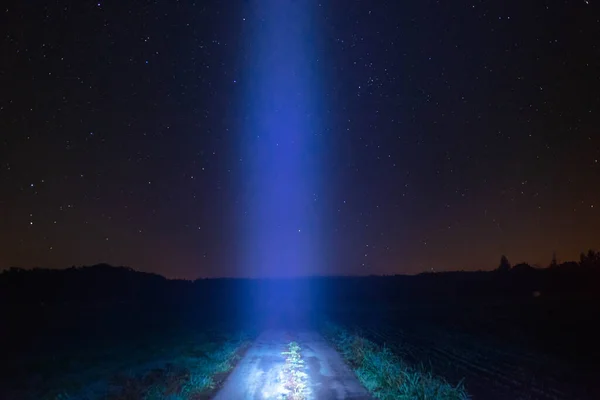 Ovanın üzerinde bulutsuz yıldızlı gökyüzü. Ortasında toprak bir yol var. Yol boyunca bir ışık izi var. UFO inişinin bir göstergesi olarak kullanılabilir..
