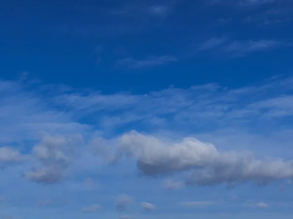 stock image The blue of the sky with single, white and gray clouds. They do not block the sun. It's a sunny day.