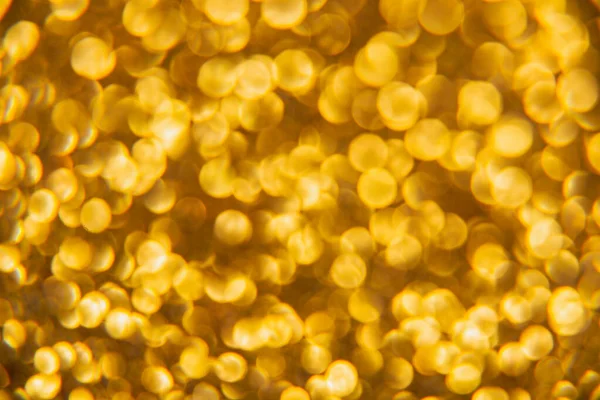 Oval sarı nesnelerden yapılmış doku. Etki, simli yüzeyi odaklanmadan makro ölçekte fotoğraflayarak elde edildi..