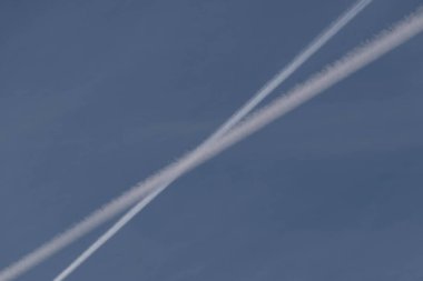 Mavi, bulutsuz gökyüzü. Gökyüzünün arka planında, jet uçuşundan kalan yoğunlaştırılmış su buharı izleri var..