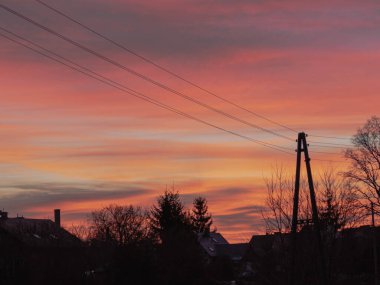 Hafif bulutlu bir gökyüzü. Akşam oldu, güneş batıyor, batan güneşin ışığı gökyüzünü kırmızıya çeviriyor..