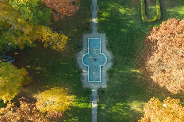 Park seen from the top in autumn. Photo taken with a drone. The leaves on the trees are yellow. It's a sunny day.