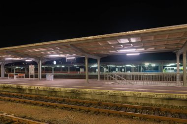 Tren istasyonu, gece demiryolu platformları, elektrik fenerleriyle aydınlatılıyor. Bulutsuz gökyüzünde yıldızları görebilirsin..