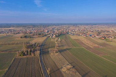 Geniş bir düzlük, tarıma elverişli tarlalar ve aralarında gri asfalt bir yol görebileceğiniz çayırlar. Güneşli bir gün. Arabalar yolda gidiyor. İHA 'dan fotoğraf..