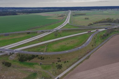 Uçsuz bucaksız, yeşil tarlalar ve çayırlar. Çerçevenin ortasında büyük bir iletişim kavşağı ve otobanda bir çatal var. Yüksek bir yerden bak. İHA 'dan fotoğraf..