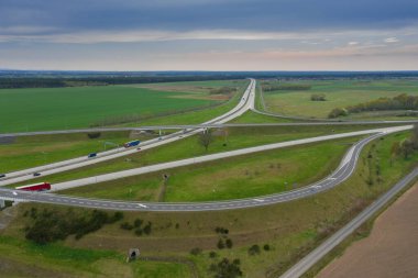 Uçsuz bucaksız, yeşil tarlalar ve çayırlar. Çerçevenin ortasında büyük bir iletişim kavşağı ve otobanda bir çatal var. Yüksek bir yerden bak. İHA 'dan fotoğraf..