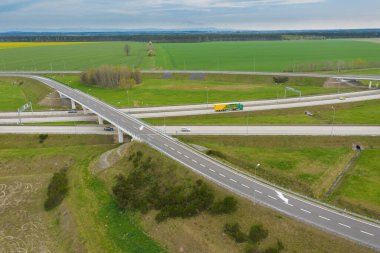 Uçsuz bucaksız, yeşil tarlalar ve çayırlar. Çerçevenin ortasında büyük bir iletişim kavşağı ve otobanda bir çatal var. Yüksek bir yerden bak. İHA 'dan fotoğraf..