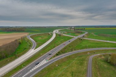 Uçsuz bucaksız, yeşil tarlalar ve çayırlar. Çerçevenin ortasında büyük bir iletişim kavşağı ve otobanda bir çatal var. Yüksek bir yerden bak. İHA 'dan fotoğraf..