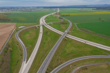 Uçsuz bucaksız, yeşil tarlalar ve çayırlar. Çerçevenin ortasında büyük bir iletişim kavşağı ve otobanda bir çatal var. Yüksek bir yerden bak. İHA 'dan fotoğraf..
