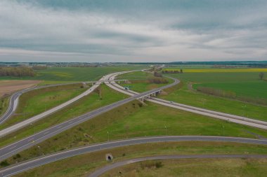 Uçsuz bucaksız, yeşil tarlalar ve çayırlar. Çerçevenin ortasında büyük bir iletişim kavşağı ve otobanda bir çatal var. Yüksek bir yerden bak. İHA 'dan fotoğraf..