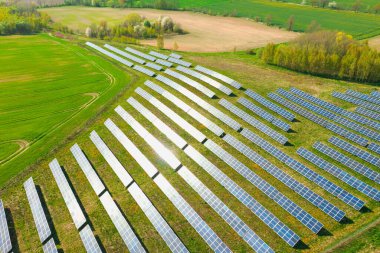 Tepenin yamaçlarındaki güneş panelleri güneş ışığıyla aydınlatılan yeşille kaplanmış. İnsansız hava aracından görüntüle.