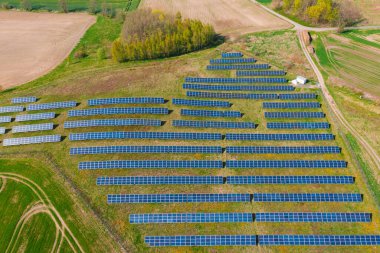 Tepenin yamaçlarındaki güneş panelleri güneş ışığıyla aydınlatılan yeşille kaplanmış. İnsansız hava aracından görüntüle.