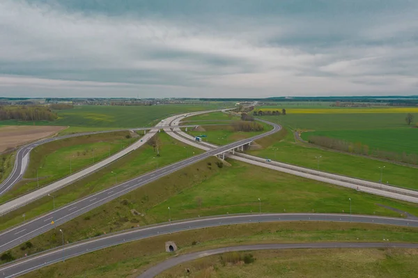 Uçsuz bucaksız, yeşil tarlalar ve çayırlar. Çerçevenin ortasında büyük bir iletişim kavşağı ve otobanda bir çatal var. Yüksek bir yerden bak. İHA 'dan fotoğraf..