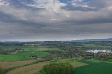 Sudeten Upland 'da. Tarıma elverişli tarlalar, çayırlar ve ormanlarla kaplı dalgalı bir arazi. Uzaktan tepeleri görebilirsin. Gökyüzü kısmen kara ve yağmurlu bulutlarla kaplı. İHA 'dan fotoğraf..