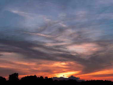 Evening, slightly cloudy sky. The clouds are colored red with the light of the setting sun. You can see the blue sky in some places.