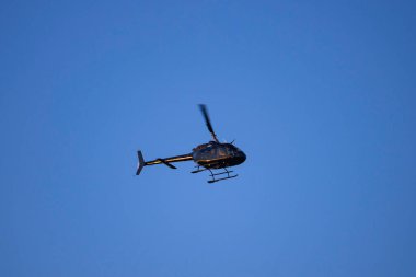 Bulutsuz mavi gökyüzüne doğru uçan küçük bir helikopter..