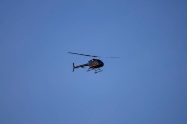Bulutsuz mavi gökyüzüne doğru uçan küçük bir helikopter..