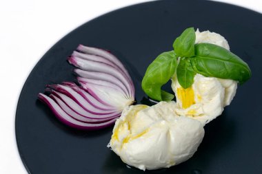 Siyah bir tabakta fesleğen ve kırmızı soğanlı Mozzarella topu.