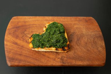 Kalp şeklinde ızgara tost, tahtanın üzerinde ıspanak ezmesi, yan görüş seçici odaklanma..