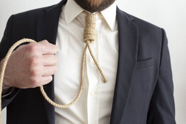 Koyu renk takım elbiseli bir erkek mikrofon olarak elinde bir ip tutuyor.