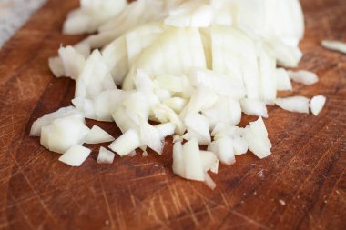 Koyu bir tahta üzerinde doğranmış soğan.