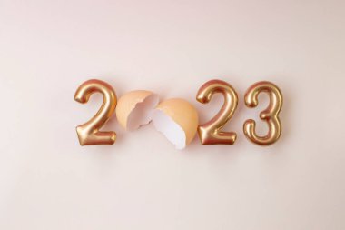 2023 altın harflerle ve yumurta kabuğuyla yazılmış, mutlu yeni yıl bej kart tasarımı