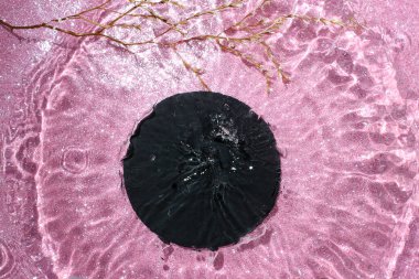 Pembe parlak arka planda yuvarlak su gölgeli siyah taş fayanslar. Su sıçrama modeli, ürün gösterimi için hareket efekti. 