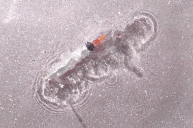 Şırınga suyu, kumlu bir parıltı dokusuna sıçrar. Pembe arka plan.. 