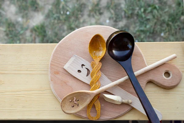 Multiple different wood spoons on a wooden chopping board