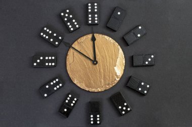 Watch with domino pieces as numbers,  and a golden stone tile in the middle,  showing 10 minutes until midnight 