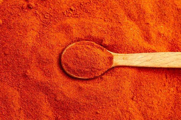 Smoked  Paprika powder background, top view close up with a wooden tea spoon. 