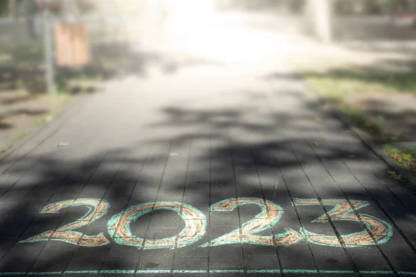 2023 number written with chalk on a park alley, new year card design