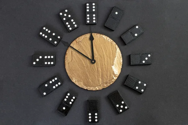 Watch with domino pieces as numbers,  and a golden stone tile in the middle,  showing 10 minutes until midnight 