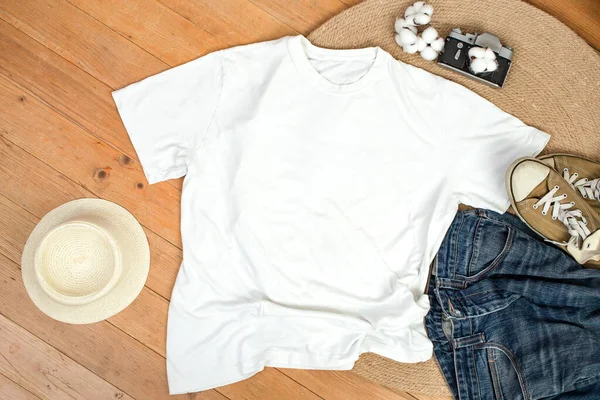 Unisex white shirt , flat lay on wooden boards with blue jeans, sneakers and cotton flowers, Creative mockup for design presentation.