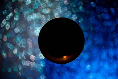 Ortasında siyah boş bir çember olan girdaplı bir bokeh. Odaklanmamış mavi simler, soyut arkaplan