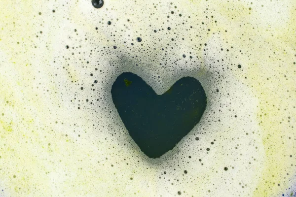 Dark green heart shape in foam, soft focus close up