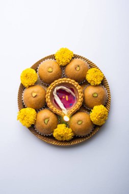 Besan ladoo ve diwali diya veya marigold çiçekleriyle süslenmiş kil lamba - Mutlu bayramlar