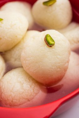 Rasgulla ya da rosogulla. Khoya 'dan yapılmış yumuşak ve süngerimsi bir Hint tatlısı. Sarı peçete ve kahverengi arka planda toprakta.