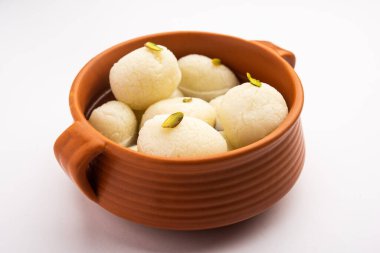 Rasgulla ya da rosogulla. Khoya 'dan yapılmış yumuşak ve süngerimsi bir Hint tatlısı. Sarı peçete ve kahverengi arka planda toprakta.