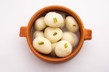 Rasgulla ya da rosogulla. Khoya 'dan yapılmış yumuşak ve süngerimsi bir Hint tatlısı. Sarı peçete ve kahverengi arka planda toprakta.