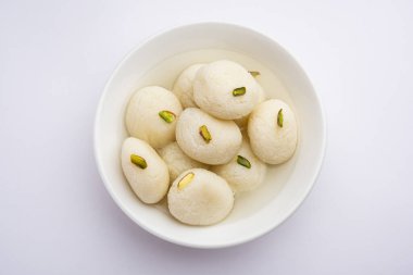Rasgulla ya da rosogulla. Khoya 'dan yapılmış yumuşak ve süngerimsi bir Hint tatlısı. Sarı peçete ve kahverengi arka planda toprakta.