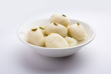 Rasgulla ya da rosogulla. Khoya 'dan yapılmış yumuşak ve süngerimsi bir Hint tatlısı. Sarı peçete ve kahverengi arka planda toprakta.
