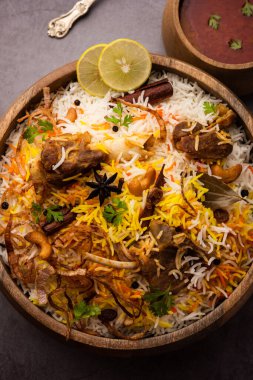 Koyun eti ya da kuzu biryani ve basmati pilavı, karamsar bir arkaplanda servis edilir..