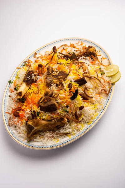 mutton or lamb biriyani with basmati rice, served in a bowl over moody background.